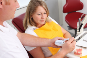Dentist showing a patient a denture that clips onto implants at a Terrigal Central Coast clinic